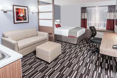 a hotel room with a bed a couch and a desk at Microtel Inn & Suites by Wyndham Fort Saint John in Fort Saint John
