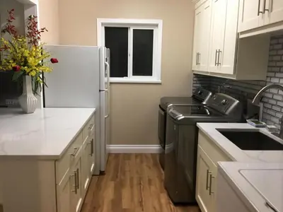 a kitchen with white cabinets and a white refrigerator at Rose Garden Vancouver Airport - Richmond BC in Richmond