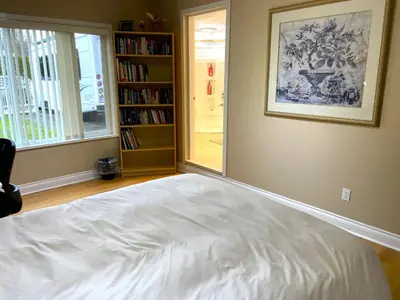 a bedroom with a white bed and a book shelf at Rose Garden Vancouver Airport - Richmond BC in Richmond