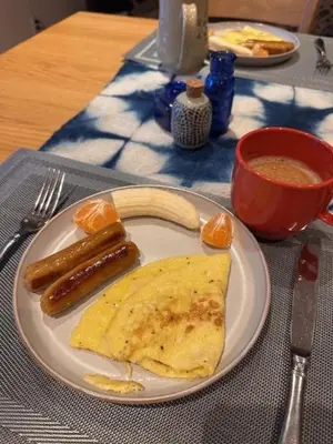 a white plate with two sausages and an omelet and a egg at The Grove B&B Mayne Island in Mayne Island