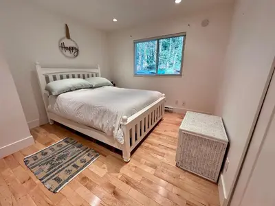 a bedroom with a white bed and a window at The Grove B&B Mayne Island in Mayne Island