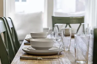 a wooden table with plates and glasses on it at Dinos Last Post - Family Friendly 4 Bedrooms in Drumheller