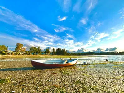 a boat sitting on the shore of a beach at Beachside Townhouses at The Pacific Shores Strata Property in Nanoose Bay