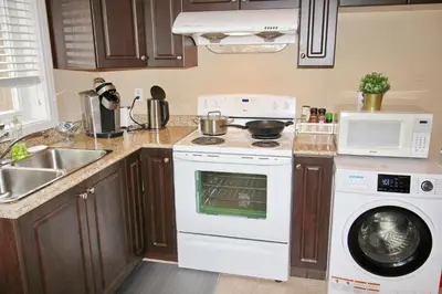 a kitchen with a stove and a washing machine at Close to YVR King Sized Private Entrance Suite in Richmond
