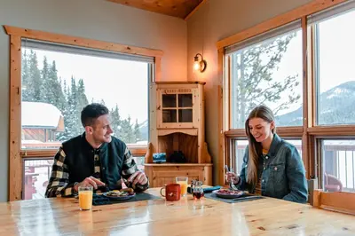 a man and woman sitting at a table eating food at Mount Engadine Lodge in Kananaskis Village