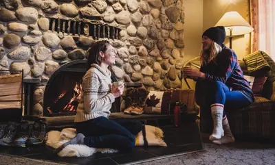 two women sitting in a living room with a fireplace at Mount Engadine Lodge in Kananaskis Village
