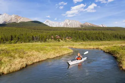 a person in a kayak on a river with mountains at Mount Engadine Lodge in Kananaskis Village