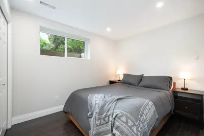 a white bedroom with a bed and a window at Elegant and Roomy Forest Getaway in North Vancouver