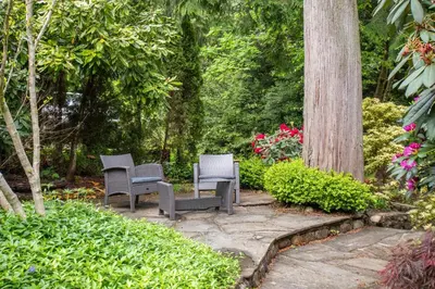 two chairs sitting on a patio in a garden at Elegant and Roomy Forest Getaway in North Vancouver