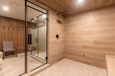 a glass shower in a bathroom with wooden walls at Alders Chalet by Fernie Central Reservations in Fernie