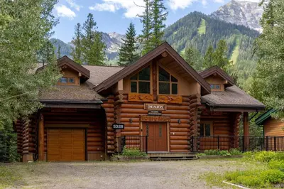 a log cabin with mountains in the background at Alders Chalet by Fernie Central Reservations in Fernie