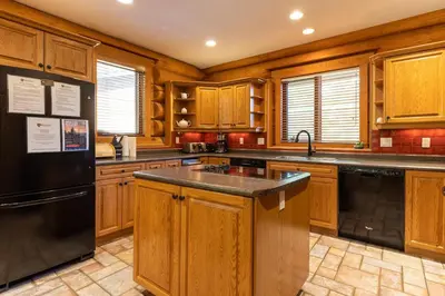 a kitchen with wooden cabinets and a black refrigerator at Alders Chalet by Fernie Central Reservations in Fernie