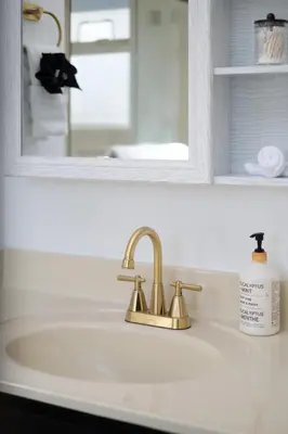 a bathroom sink with a gold faucet and a mirror at 3BR Near Commercial Dr 10 min to Downtown in Vancouver