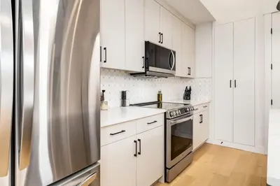 a kitchen with white cabinets and a stainless steel refrigerator at Perfect for Long Stays Free Parking Pets Allowed in Calgary