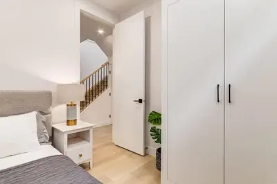 a bedroom with white walls and a bed and a staircase at Perfect for Long Stays Free Parking Pets Allowed in Calgary
