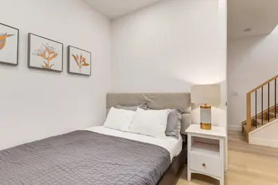 a white bedroom with a bed and a night stand at Perfect for Long Stays Free Parking Pets Allowed in Calgary