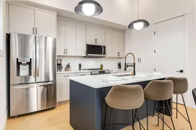 a kitchen with a refrigerator and a counter with stools at Perfect for Long Stays Free Parking Pets Allowed in Calgary
