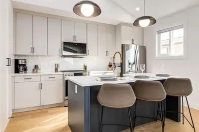 a kitchen with white cabinets and a kitchen island with stools at Free Parking, Perfect Family Home with King Bed in Calgary