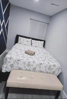 a small bedroom with a bed and a bench at A new luxury basement apartment in Surrey