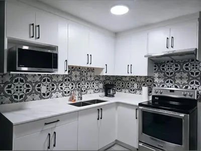 a kitchen with white cabinets and a black microwave at A new luxury basement apartment in Surrey