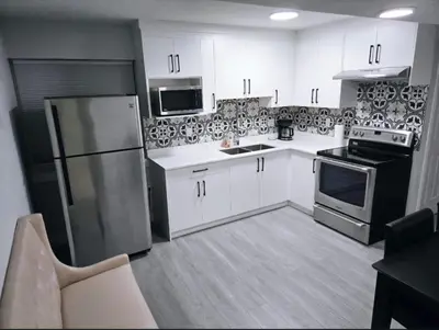 a kitchen with white cabinets and a stainless steel refrigerator at A new luxury basement apartment in Surrey