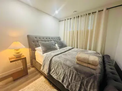 a bedroom with a bed and a lamp and a window at Comfy Neutral Living Free Parking in Calgary