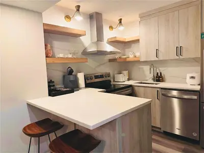 a kitchen with a white counter top and wooden cabinets at Comfy Neutral Living Free Parking in Calgary