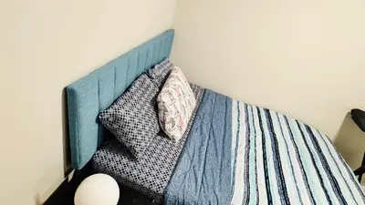 a bed with a blue headboard with two pillows at Tee's Oasis in Calgary