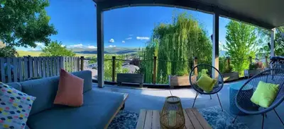 a living room with a blue couch and a large window at Licensed 2-Bedroom Suite Eco-Friendly Solar Home in Kelowna