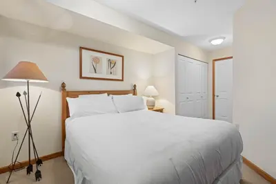 a bedroom with a large white bed and a lamp at Nicklaus North - Clubhouse by Whistler Premier in Whistler