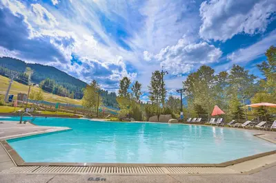a large swimming pool with chairs and a mountain at Toby Creek Lodge by StayIn in Panorama