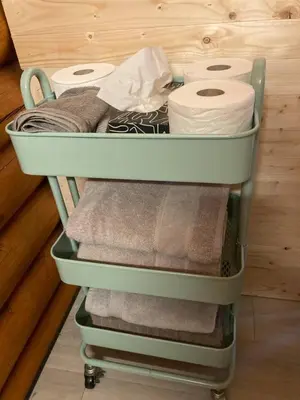 a green cart with towels and toilet paper at Lofted log cabin with fire table in Kelowna