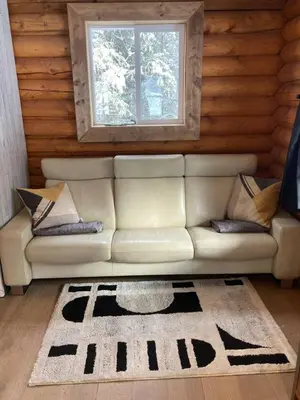 a living room with a white couch and a window at Lofted log cabin with fire table in Kelowna