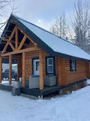a log cabin with a snow covered roof at Lofted log cabin with fire table in Kelowna