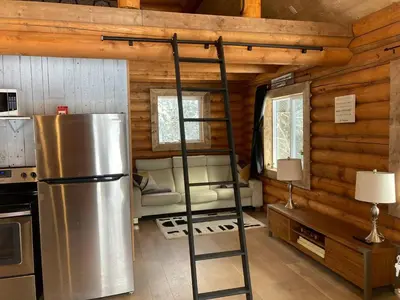a loft bed in a log cabin with a refrigerator at Lofted log cabin with fire table in Kelowna