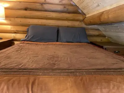a large bed in a log cabin bedroom at Log lofted rustic cabin in woods in Kelowna