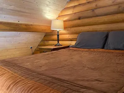 a bedroom with a bed in a log cabin at Log lofted rustic cabin in woods in Kelowna