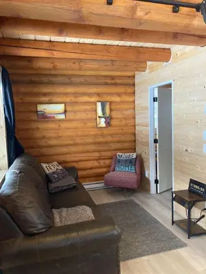 a living room with a leather couch and a chair at Log lofted rustic cabin in woods in Kelowna