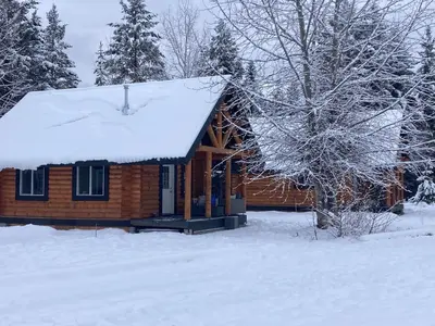 a log cabin with snow on the roof at Log lofted rustic cabin in woods in Kelowna
