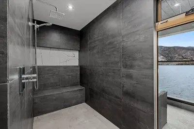 a bathroom with a shower and a glass door at Nest Luxury Modern Lake House in Penticton
