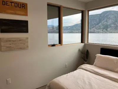 a bedroom with a bed and a view of the water at Nest Luxury Modern Lake House in Penticton
