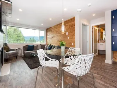 a dining room and living room with a glass table and chairs at Whistler Village Center - Newly Renovated Condo in Whistler