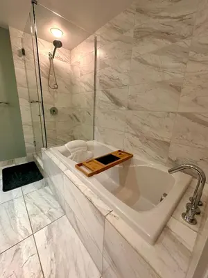 a white bathroom with a tub and a shower at Century Park Condo Oasis in Edmonton