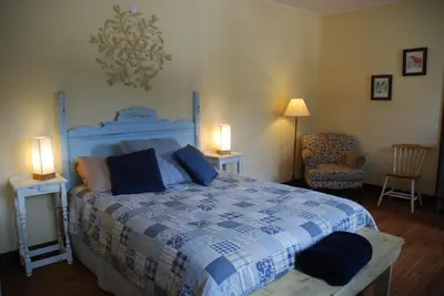 a bedroom with a bed and two tables and a chair at Victoria Falls House Inn in Nelson