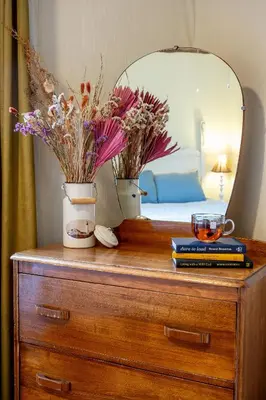 a wooden dresser with a mirror and flowers on it at Victoria Falls House Inn in Nelson