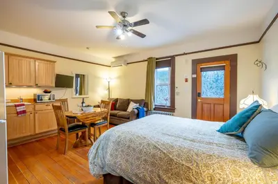a bedroom with a bed and a table and a kitchen at Victoria Falls House Inn in Nelson