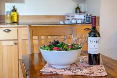 a bowl of salad and a bottle of wine on a table at Victoria Falls House Inn in Nelson