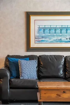 a black leather couch in a living room with a painting at Vista in Fairmont Hot Springs
