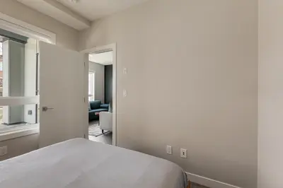a white bedroom with a bed and a living room at Free Parking, Close to Downtown, Pet Friendly in Calgary