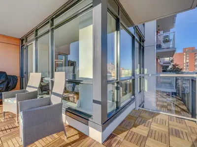 a balcony with glass walls and a table and chairs at Escher Escape - Art-filled retreat with work desk by Victoria Prime! in Victoria